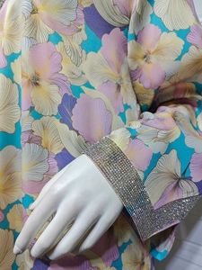 Détail des poignets en strass sur une robe à manches longues bleue avec imprimés floraux