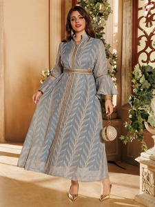 Detail of elegant light blue maxi dress with gold leaf patterns and ethnic woven trim