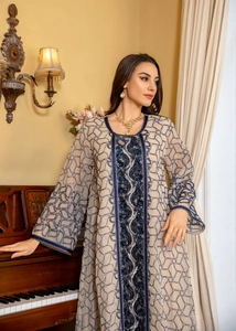 Close-up of sequined embroidery and blue trim on a beige mesh long sleeve kaftan dress