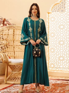 Détail de broderie géométrique dorée sur une abaya vert foncé à manches évasées