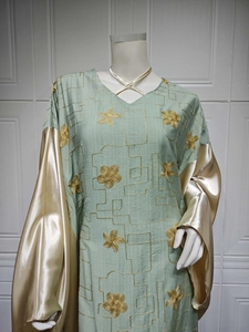 Detail of sage green fabric with gold embroidery and contrast champagne satin sleeves