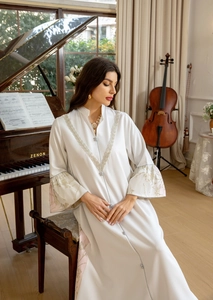 Detail of floral gold embroidery on bell sleeves of a white V-neck jacquard maxi dress