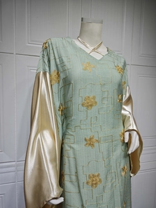 Close-up of mint green embroidered caftan with golden floral patterns and satin sleeves