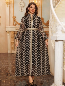 Detail of elegant black long dress with golden leaf embroidery and sheer bell sleeves