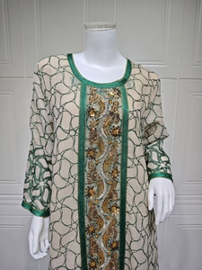 Detail of green mesh embroidery and golden sequins on elegant beige long sleeve dress