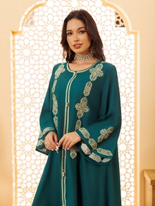 Broderie géométrique dorée détaillée sur une robe longue ethnique de couleur vert foncé