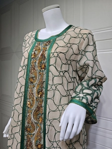 Detail of green embroidery and sparkling sequins on beige ethnic kaftan mesh dress