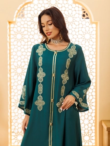 Détail de la broderie ethnique sur abaya vert foncé avec motifs dorés et boutons perlés