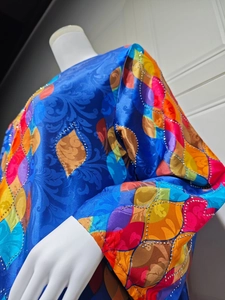 Detail of royal blue satin dress featuring floral patterns and silver rhinestone trims