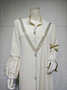 Detailed view of silver floral embroidery and wide flare sleeves on a cream kaftan