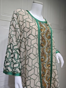Detail of sequin embroidery and intricate green patterns on beige kaftan dress