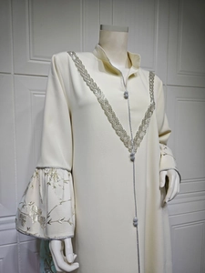 Detail of elegant cream abaya featuring silver embroidery and bell-shaped ruffled sleeves