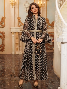 Detail of elegant black and gold flared sleeve maxi dress with gold leaf patterns and belt