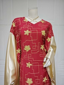 Close-up of golden floral embroidery and champagne satin sleeves on red kaftan dress