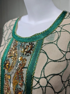 Detail of emerald green sequin embroidery and intricate mesh lacework on woman dress