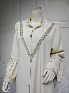 Macro view of ivory kaftan dress showing silver embroidery and trumpet sleeve details