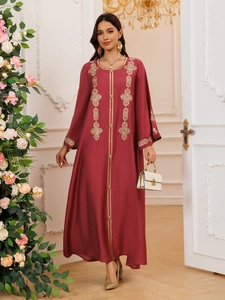 Détail de la broderie géométrique dorée sur une robe longue ethnique rouge foncé élégante