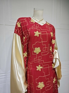 Detail of red embroidered dress with gold satin sleeves and intricate floral patterns