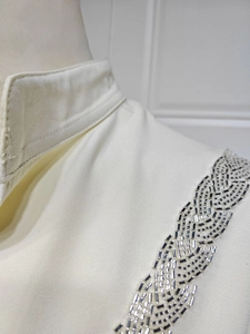 Detailed view of luxury silver bead and sequin embroidery on an ivory fashion dress