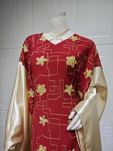 Detail of red ethnic dress featuring gold floral embroidery and shiny satin sleeves