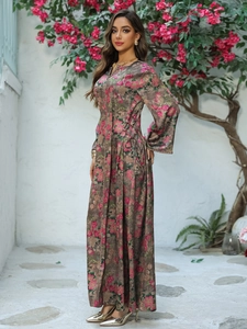 Full view of floral print Kaftan dress with V-neckline and gold trim in a sunny garden