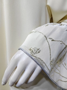 Detail of floral vine embroidery and silver piped cuff on ivory jacquard dress