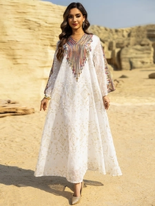 Détails de broderie colorée et motifs dorés sur une robe caftan blanche élégante