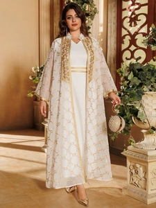 Detail eines eleganten weißen Cardigans und Kleides mit goldener Ethno-Stickerei