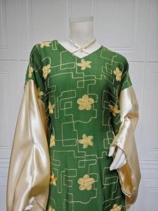 Close-up of dark green caftan with gold flower embroidery and champagne satin flared sleeves