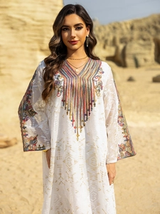 Détail de la robe caftan blanche avec broderies dorées et ornements de paillettes