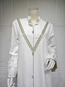 Detail of silver jacquard embroidery and decorative ball buttons on a white maxi dress