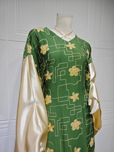 Detail of green kaftan with gold floral embroidery and champagne satin bell sleeves