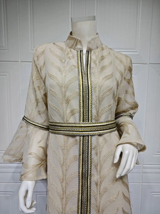 Detailed close-up of golden leaf embroidery and woven belt on the elegant kaftan dress