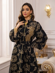 Detailed close-up of golden leaf embroidery and phoenix pattern on black Jalabiya dress