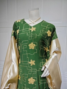 Detailed embroidery and golden satin sleeve on a dark green V-neck long dress