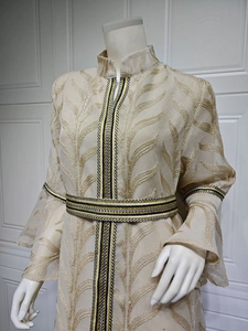 Detail of elegant gold leaf embroidery and woven trim on champagne long flare sleeve dress