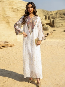 Détail de broderie sur robe de soirée abaya en maille blanche avec fleurs ethniques