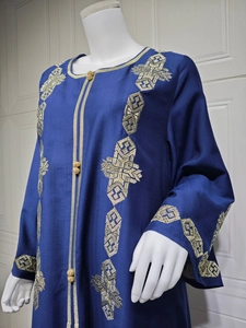Détail de la broderie dorée et des boutons sphériques sur la robe en velours bleu