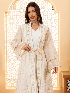 Détail de la robe en maille blanche avec broderies dorées et décolleté en V chic