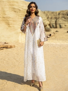 Détails de broderies colorées et perles complexes sur une robe caftan blanche