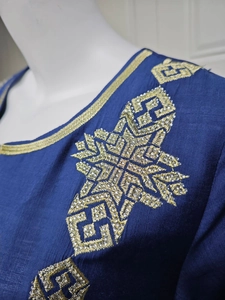 Détail d'une robe en satin bleu marine avec broderie étoilée dorée et strass scintillants