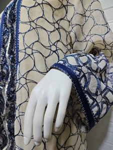 Detailed close-up of sequin embroidery and mesh fabric on a stylish beige dress sleeve