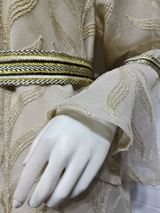 Detail of beige kaftan featuring leaf-shaped sequin embroidery and woven waist belt