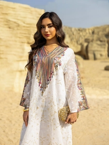 Détail de la broderie ethnique et des glands sur une robe caftan en maille blanche