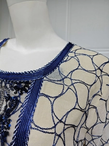 Detail of sequin embroidery and chain stitch patterns on a mesh fashion dress