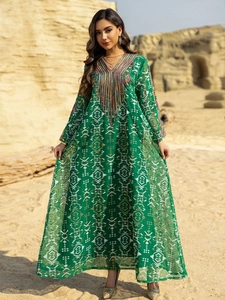 Détails de broderies ethniques et pompons sur robe longue vert foncé brodée