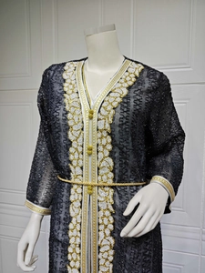 Nahaufnahme der aufwendigen weißen Stickerei und Goldkordel am schwarzen Kaftan.