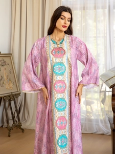 Détail d'une robe longue rose avec broderies florales et manches cloches sur un mannequin