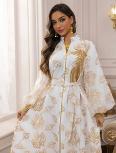 Detail of white Jalabiya dress with gold maple leaf embroidery and woven trim