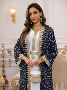 Détail du cardigan en mousseline bleue avec imprimé plumes dorées et franges colorées